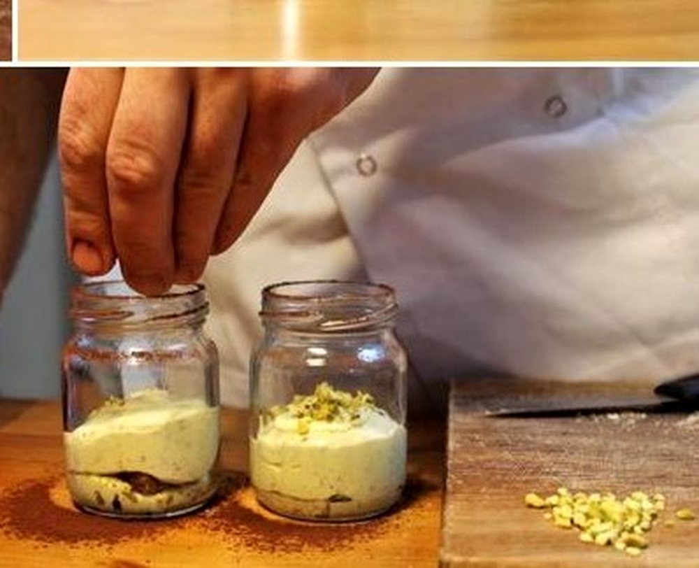 Two jars of tiramisù being layered by hand